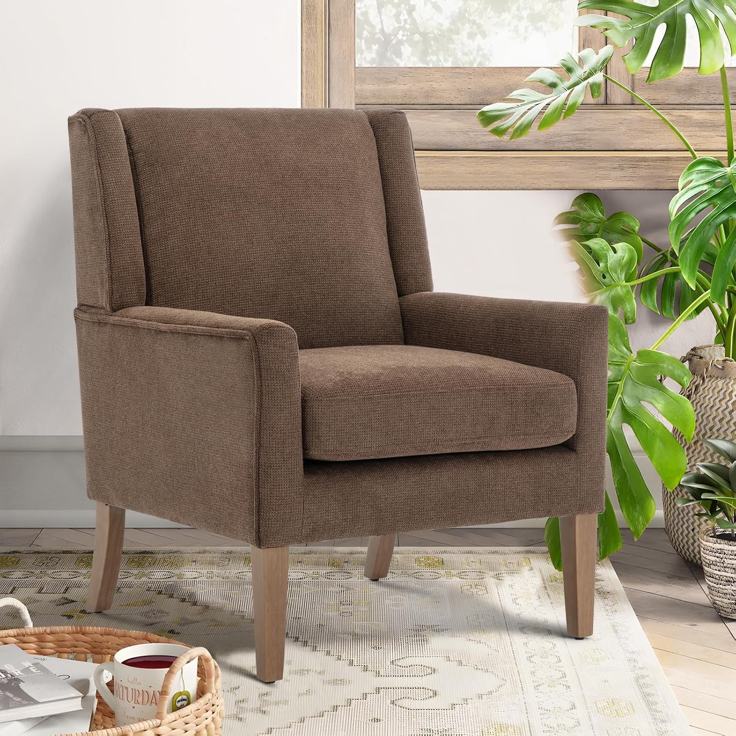 Close-up brown chenille wingback chair with tapered wood legs beside a window and potted plant.
