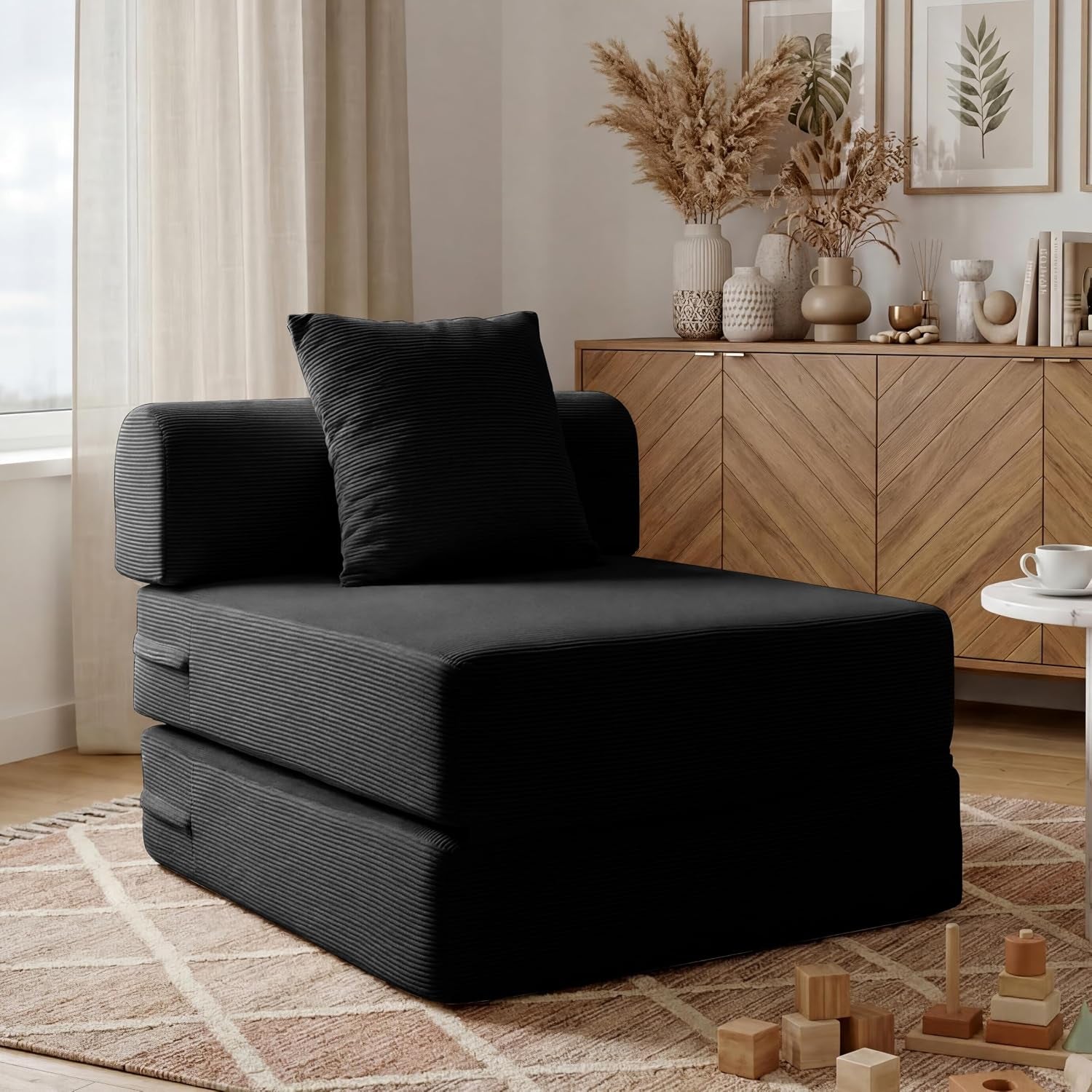 Black corduroy folding chair configuration with matching pillow beside a wooden sideboard.
