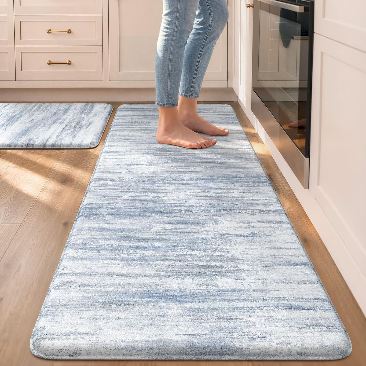 Blue-toned runner and small mat with person standing on the runner beside an oven