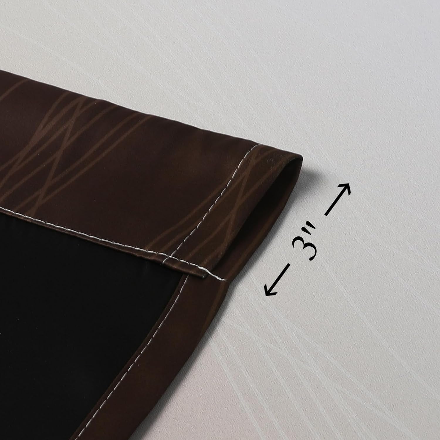 Close-up of a stitched curtain hem and black backing laid flat, with a measurement arrows graphic nearby