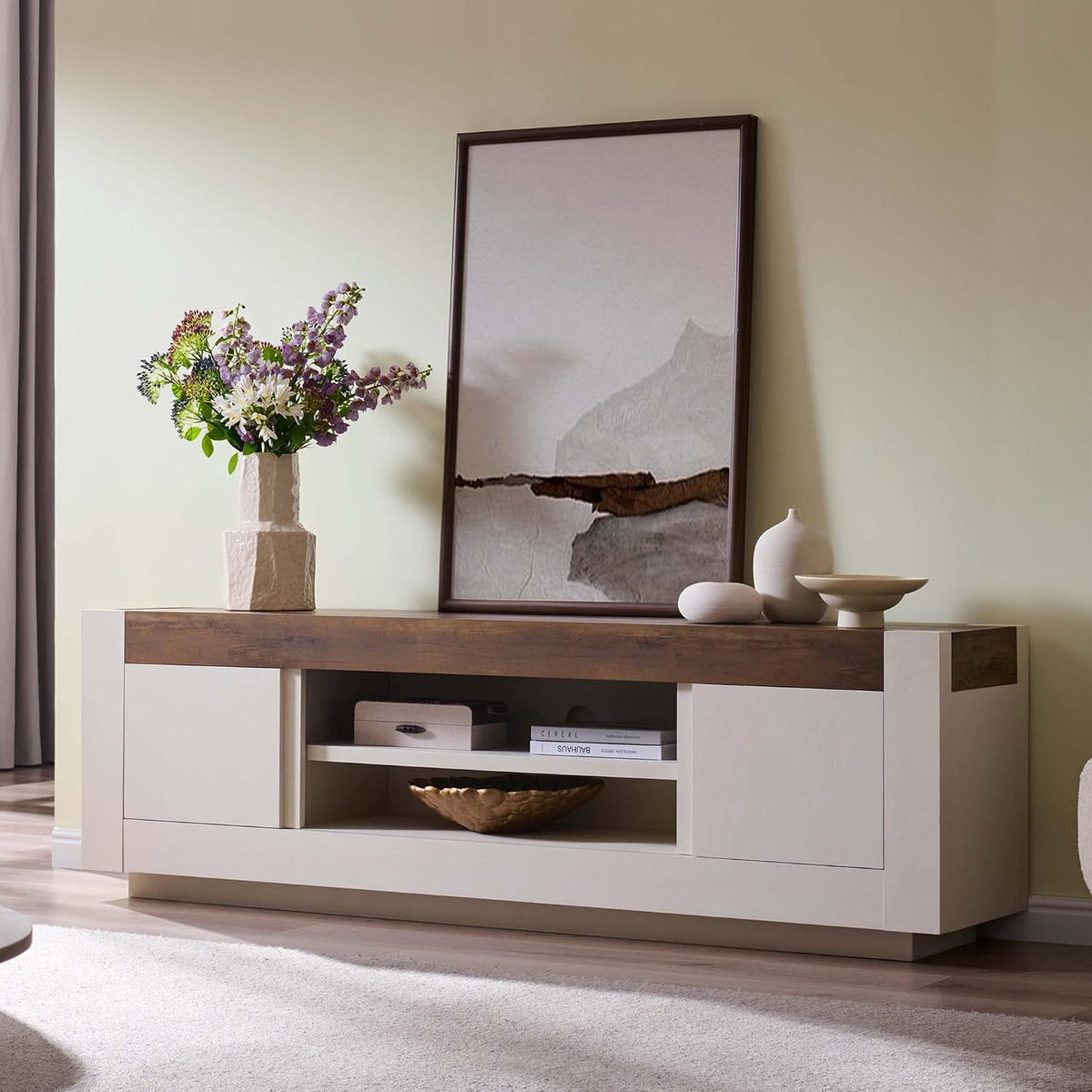 Antique white TV stand with wood-grain top styled beneath framed art
