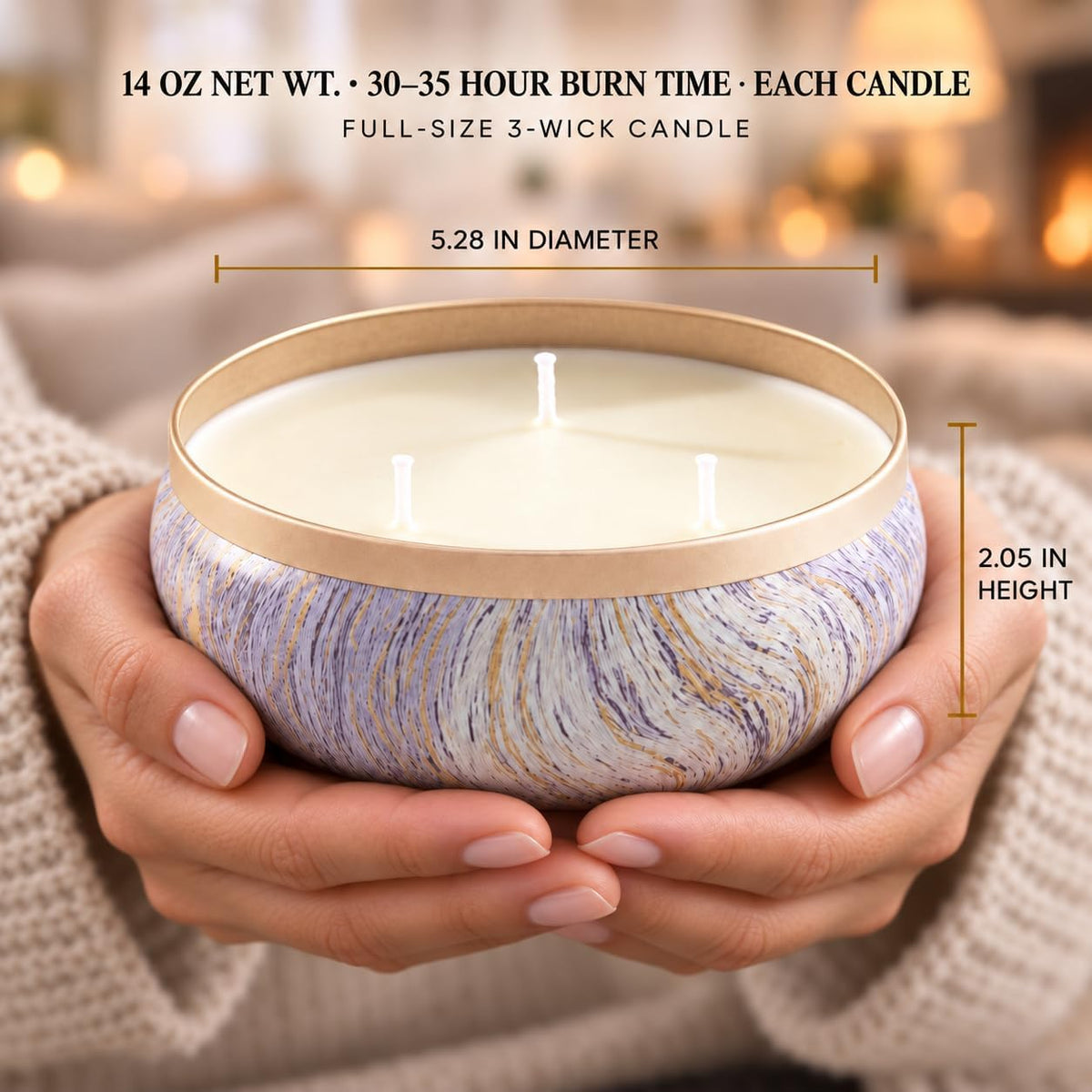 Hands cradling a low-profile marbled tin candle with three wicks, showing the wide opening and rounded shape