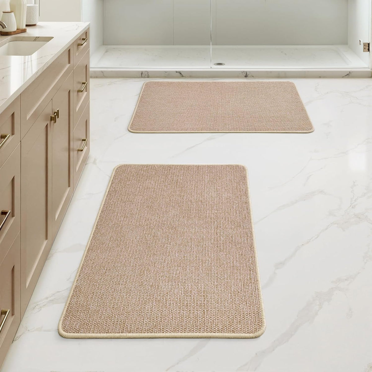 Pair of rectangular tan-beige bath rugs arranged down the length of a bathroom floor.