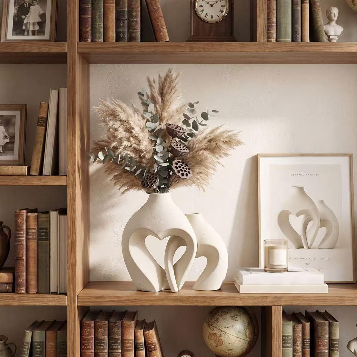 Heart-shaped ceramic vases displayed on a wooden bookshelf among books and framed art