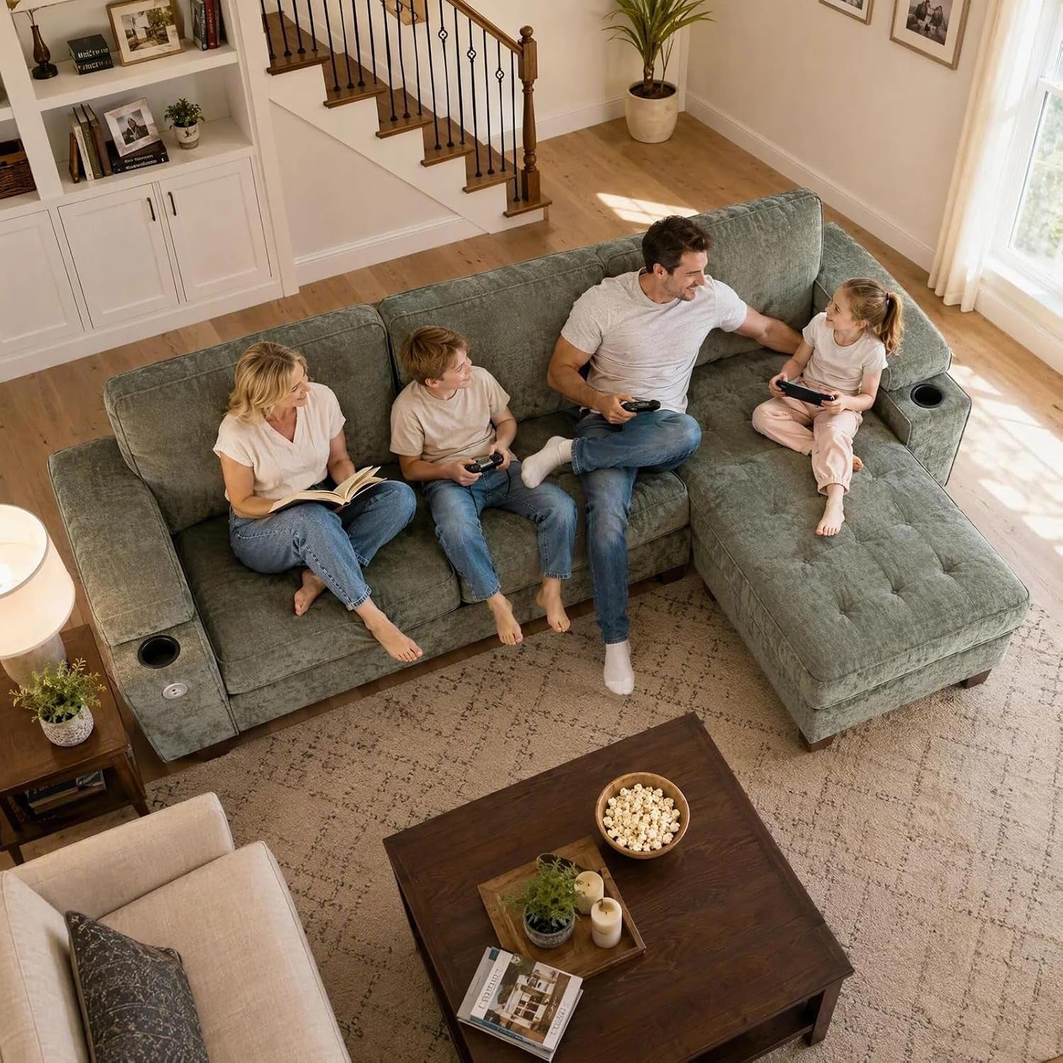 Overhead view of a family of four sitting on a chaise loveseat in a bright living room.