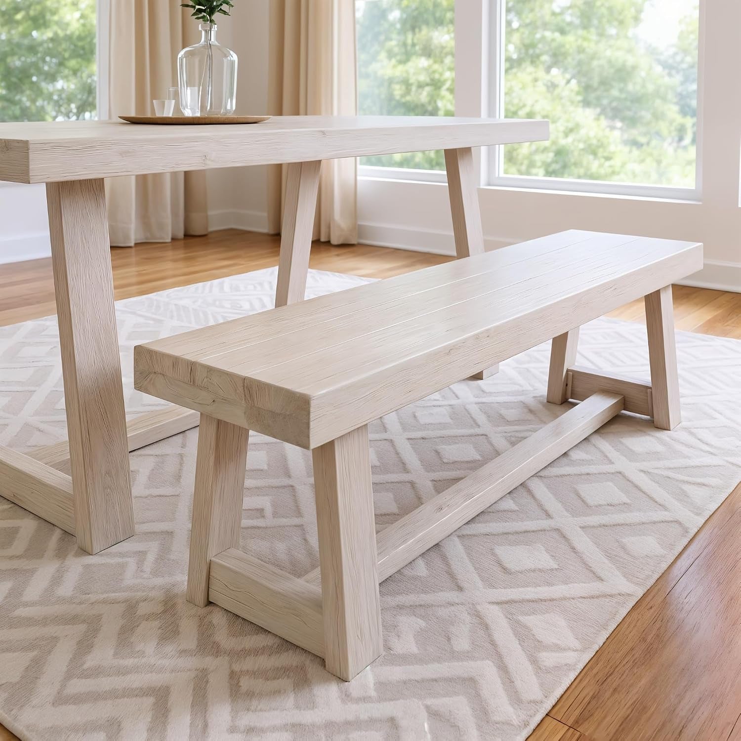 Light bleached wood bench and table set on a geometric rug near large windows