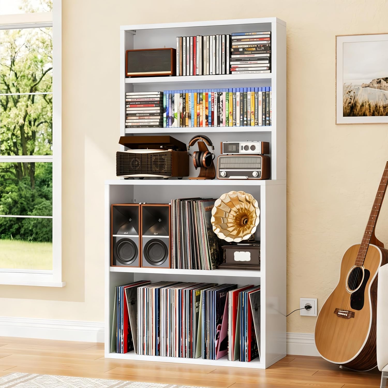 White media bookshelf stocked with records, vintage radios and speakers next to an acoustic guitar by the wall.