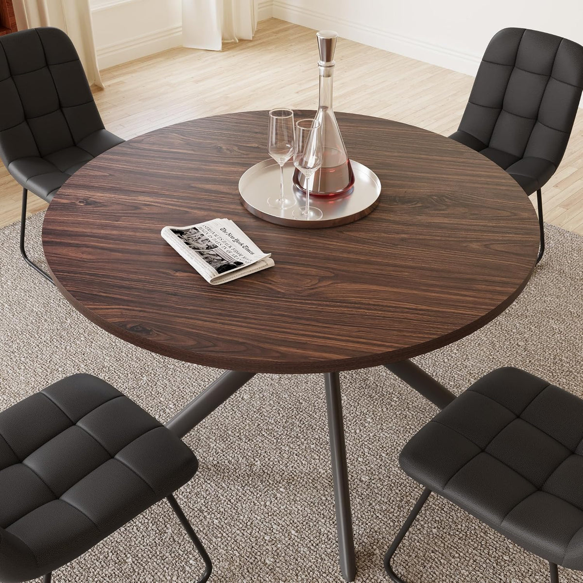 Overhead view of round walnut tabletop with a tray and surrounding black upholstered chairs