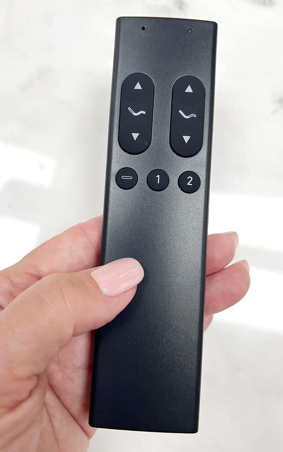Black wireless remote control held in hand showing up/down buttons and memory preset keys.