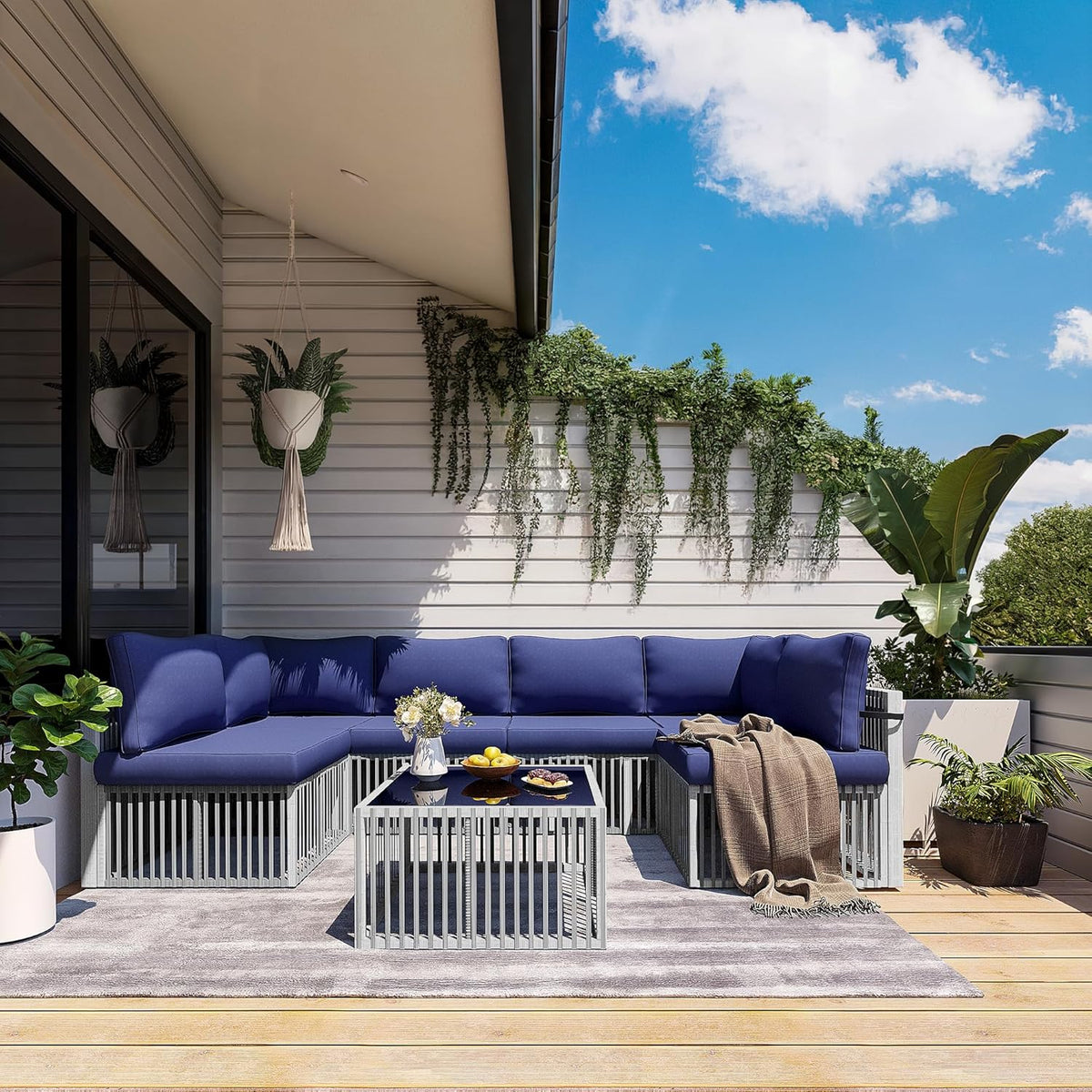 Balcony seating area with L-shaped rattan sofa fitted with deep blue cushions and a slatted coffee table on a rug.