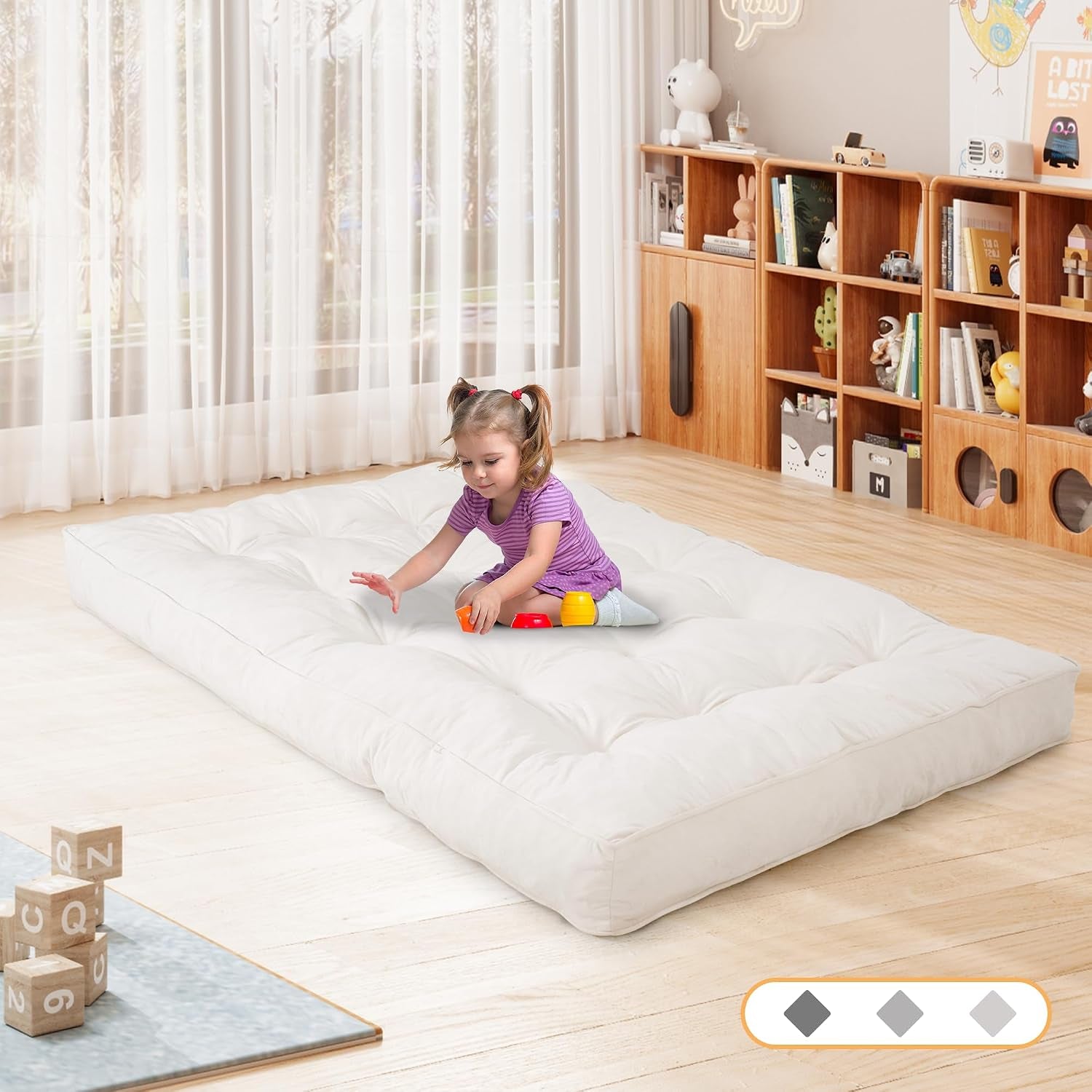 Child playing on a white futon floor mattress in a playroom setting