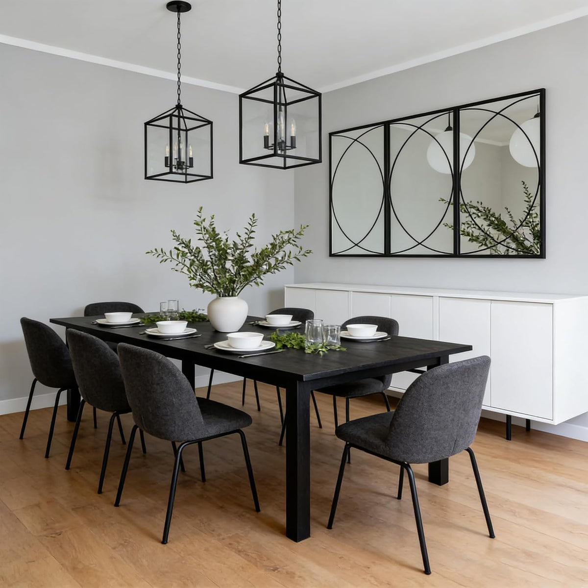 Three black rectangular mirrors with circular metal accents hung above a white sideboard in a dining room
