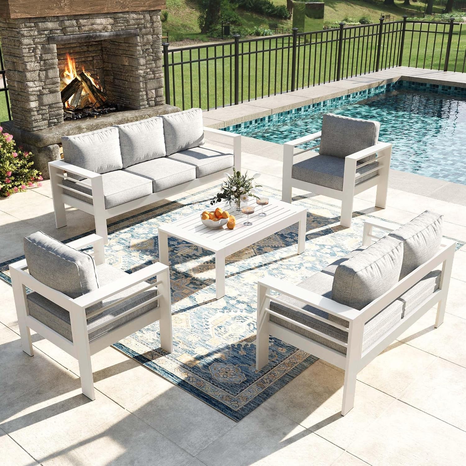 Higher-angle view of the white patio set showing two armchairs and a loveseat facing a slatted coffee table.