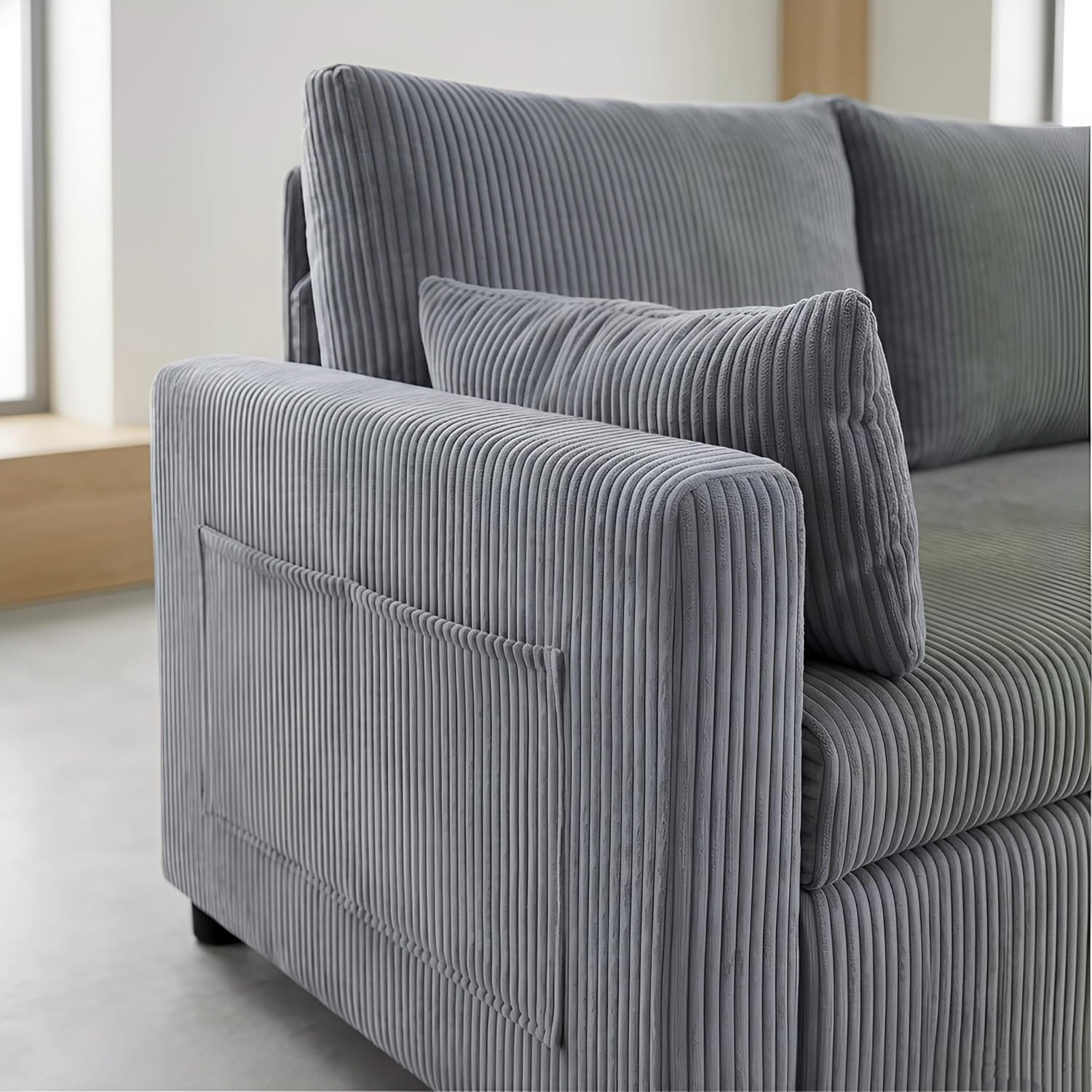 Close-up of the sofa's squared arm with a stitched outer pocket in gray ribbed fabric.