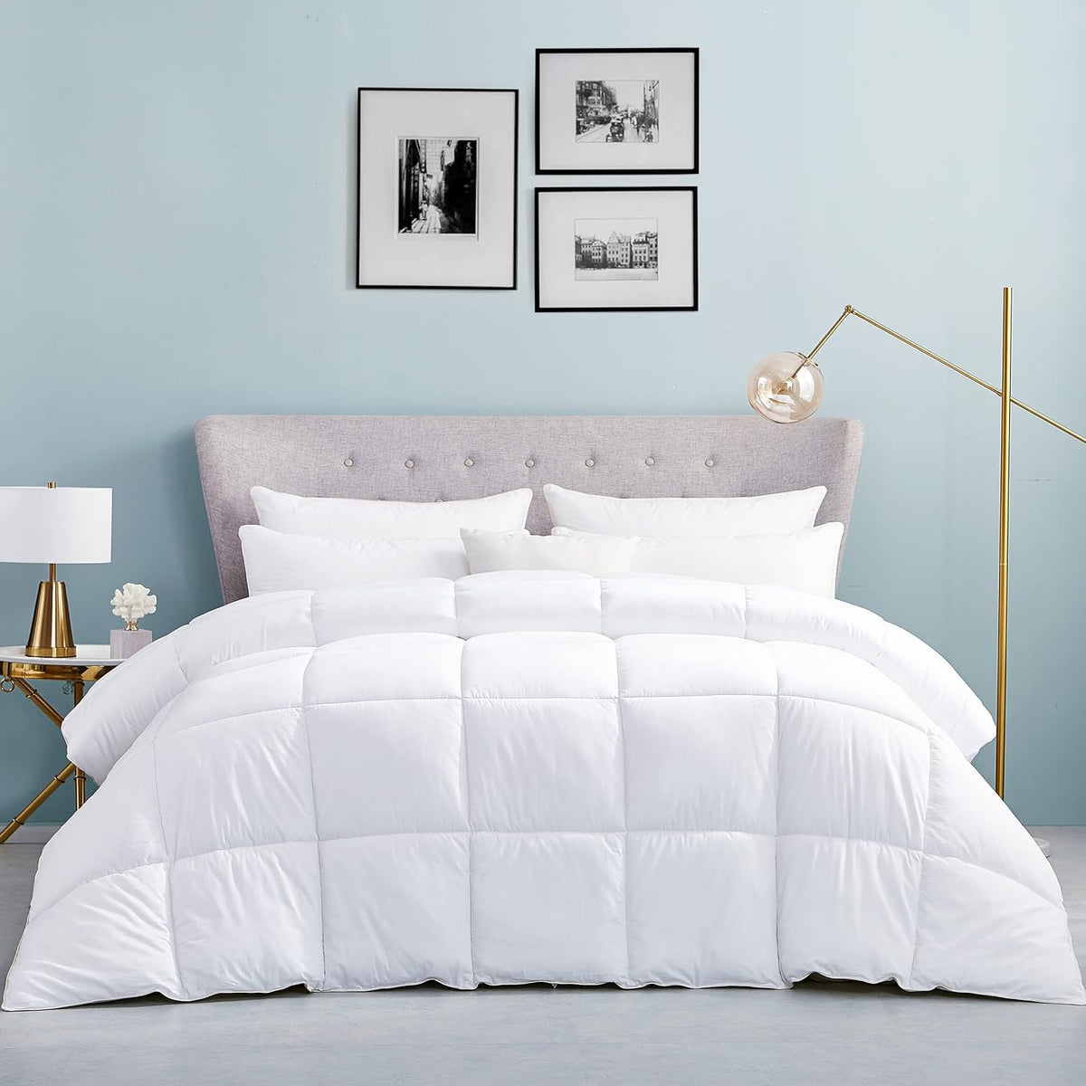 Front view of a bed dressed in a white box‑stitched comforter with tufted headboard and bedside lamp