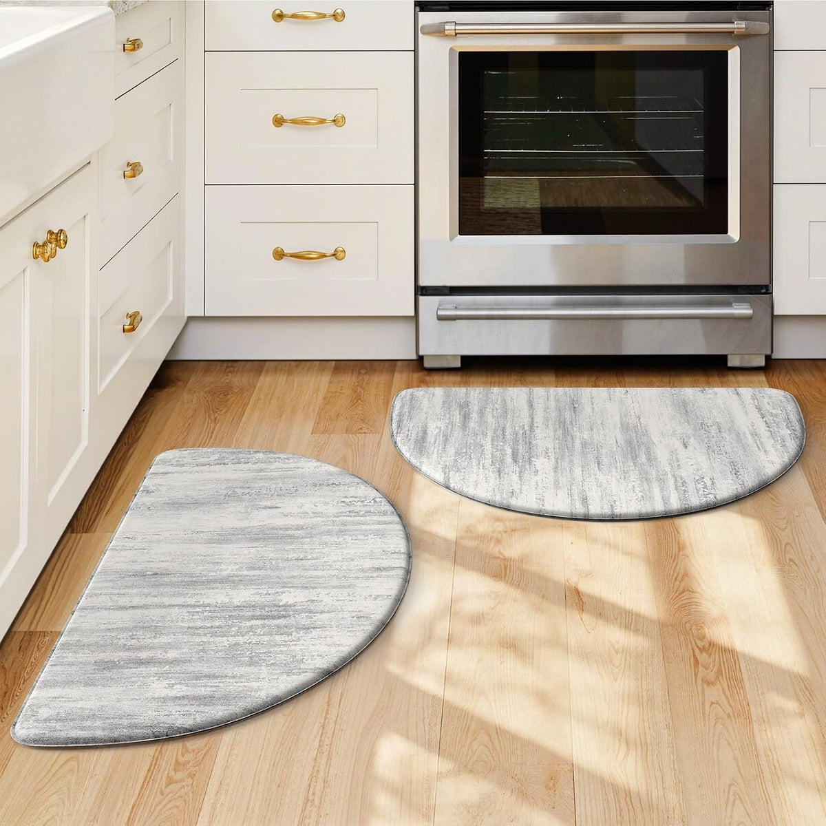 Two semicircular gray abstract kitchen mats on wood floor in front of oven and cabinets.