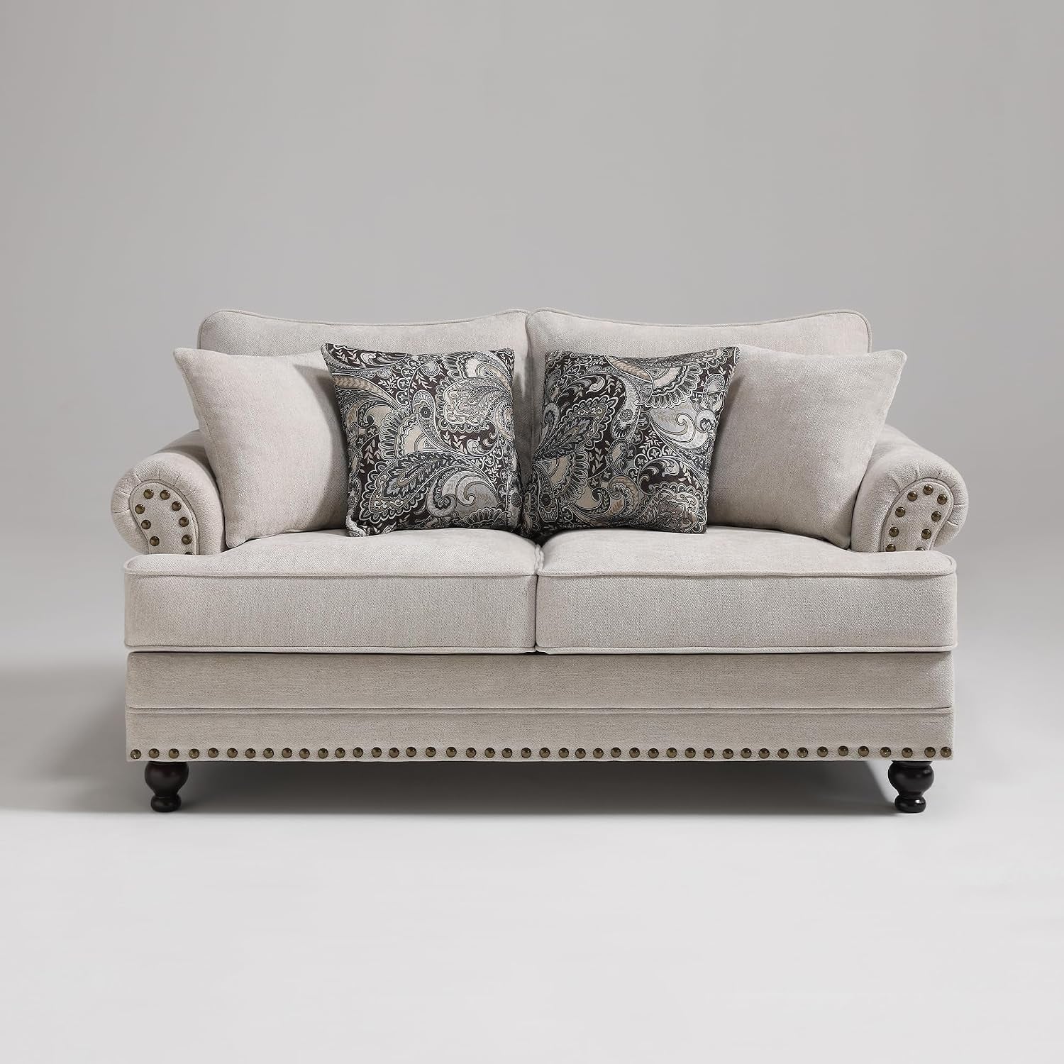 Two-seat loveseat in beige chenille with rolled arms, paisley throw pillows, nailhead trim and dark wooden legs.