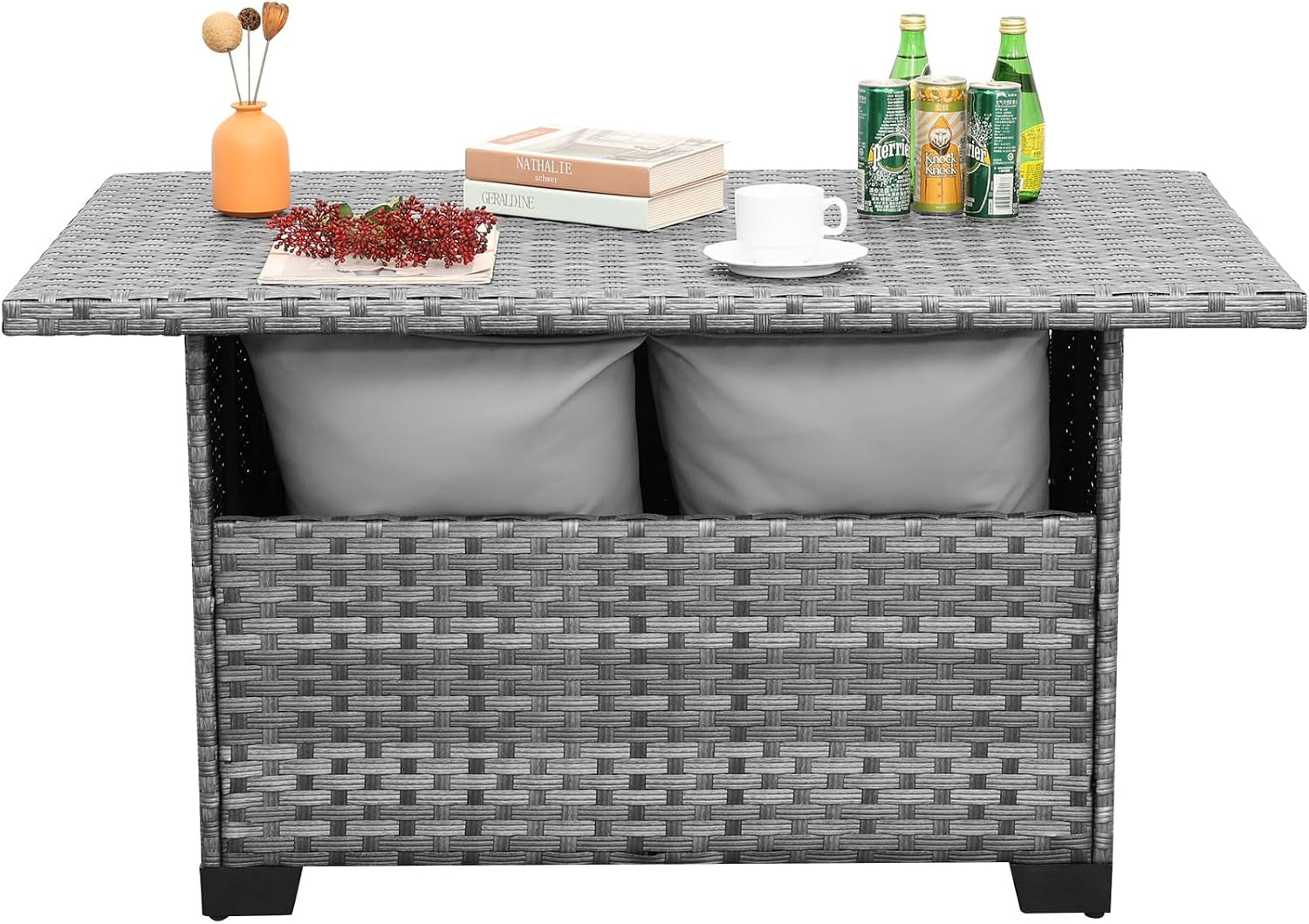 Front-facing studio view of grey wicker storage patio table with two cushions visible inside the open storage compartment