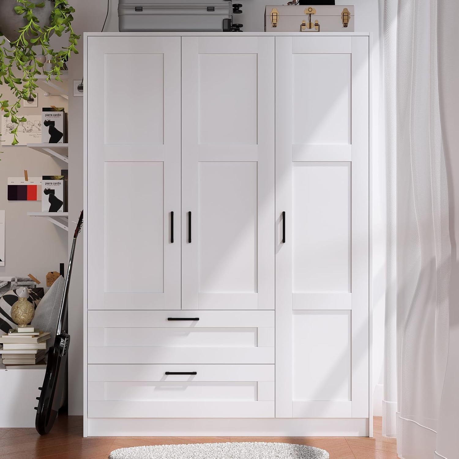 Front-facing view of white 3-door wardrobe with two lower drawers and black handles in a bright room