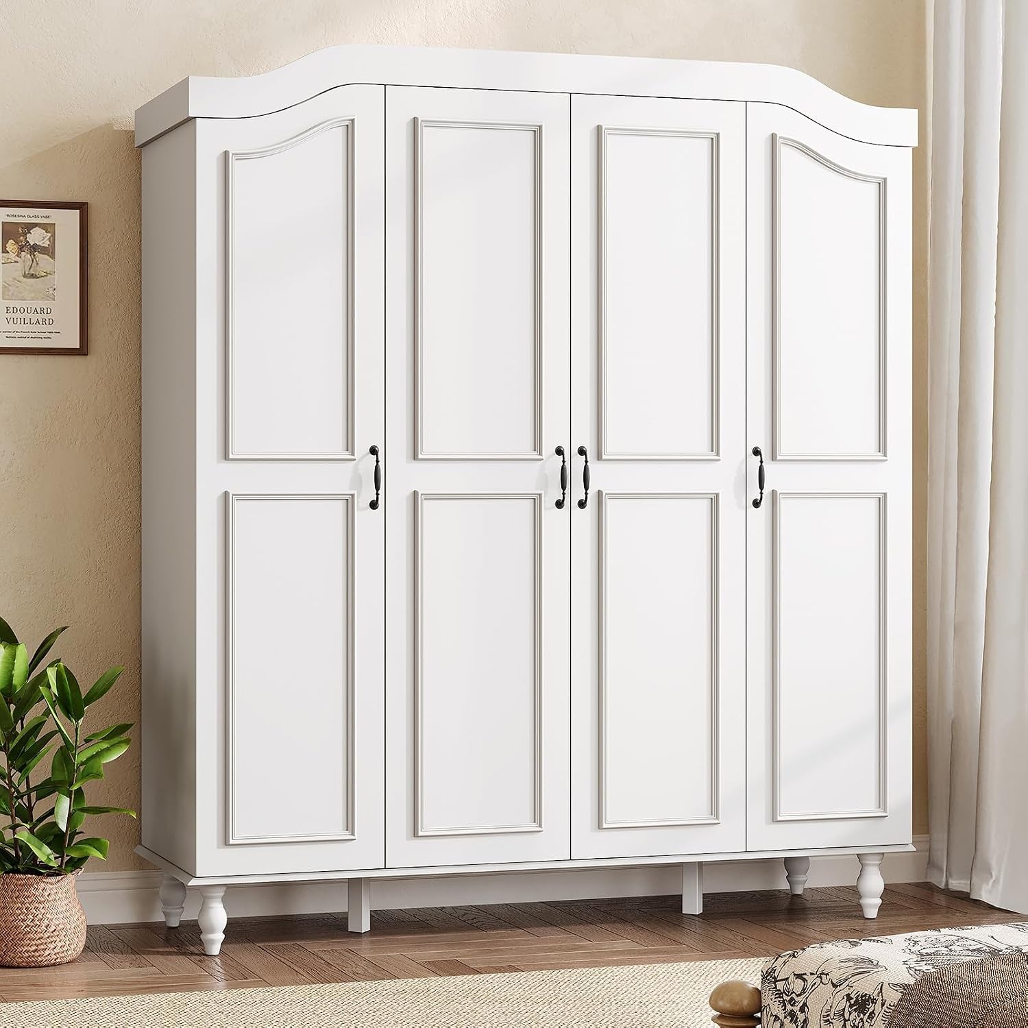 Front view of a white four-door armoire with an arched top and turned legs against a beige wall.