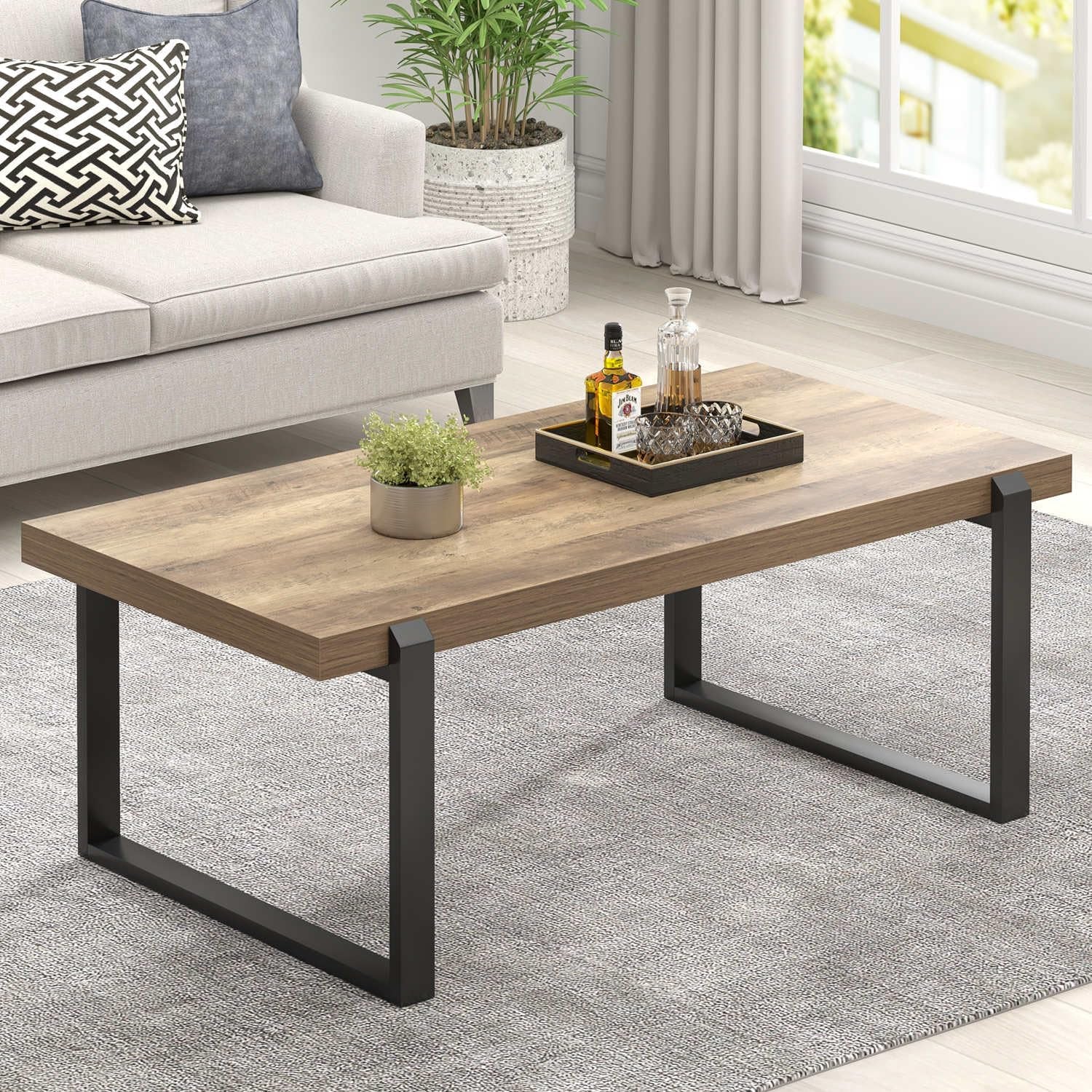 Rustic oak wood-grain coffee table with black metal U-shaped legs, angled front view in a living room setting.
