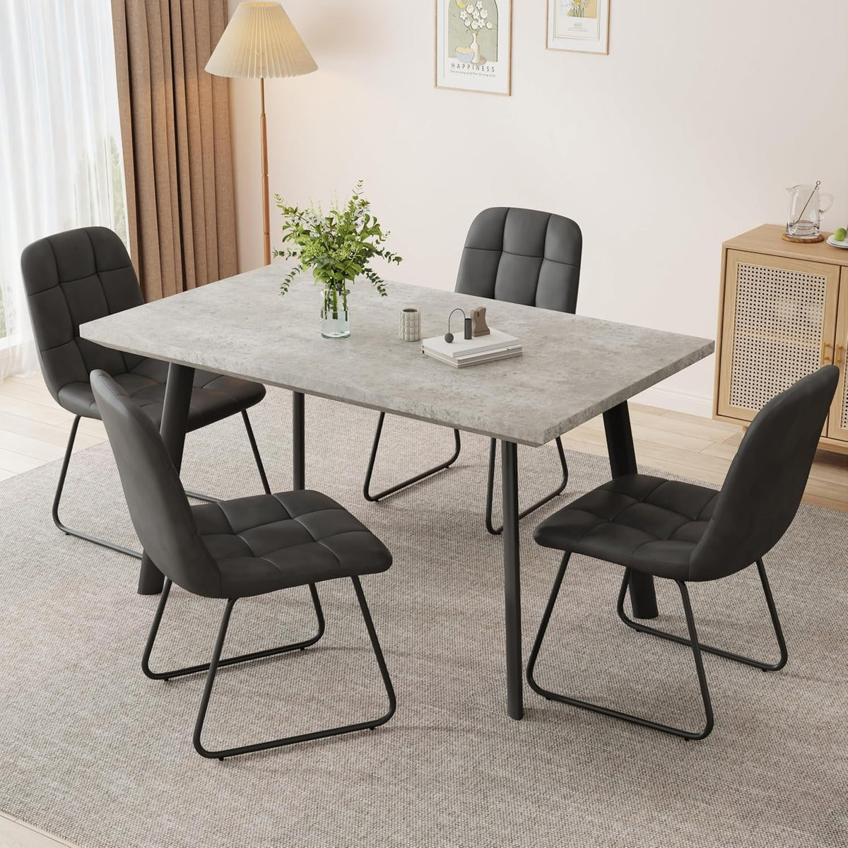 Concrete-look tabletop surrounded by quilted dark chairs with black sled-style metal bases in a softly lit dining corner.