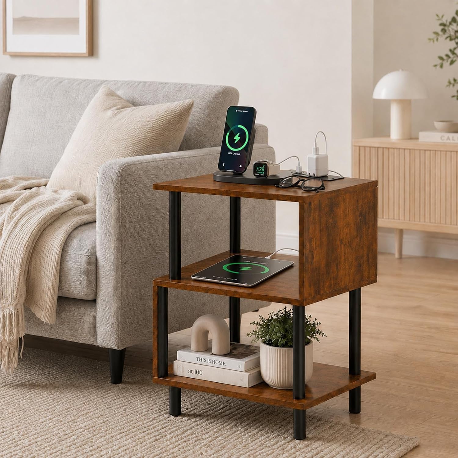 Rustic brown three-tier side table staged with phone charger, books and a potted plant