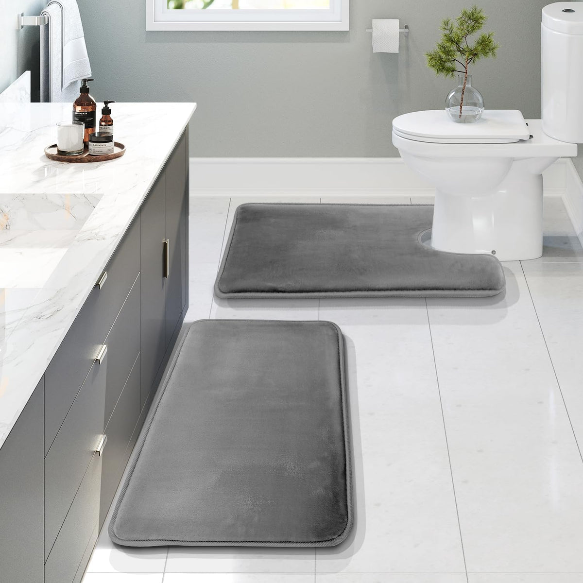 Bathroom scene with three charcoal-gray memory foam mats arranged by a vanity and toilet.