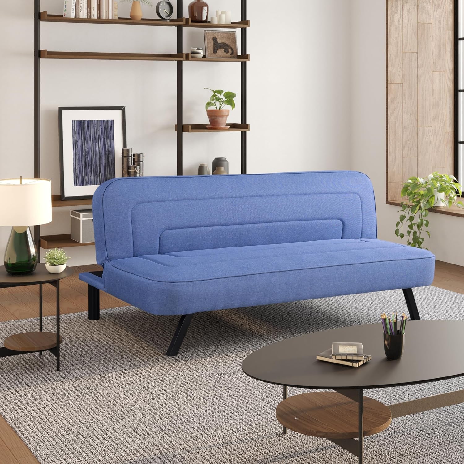 Blue upholstered convertible futon sofa angled front view in a bright living room