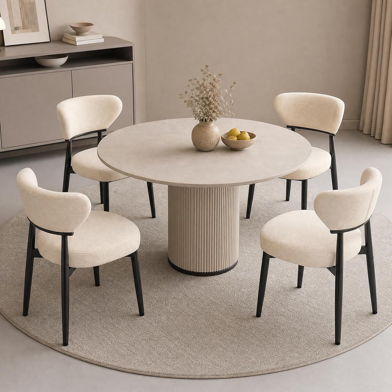 Four beige upholstered dining chairs with curved backs and black legs around a round table.