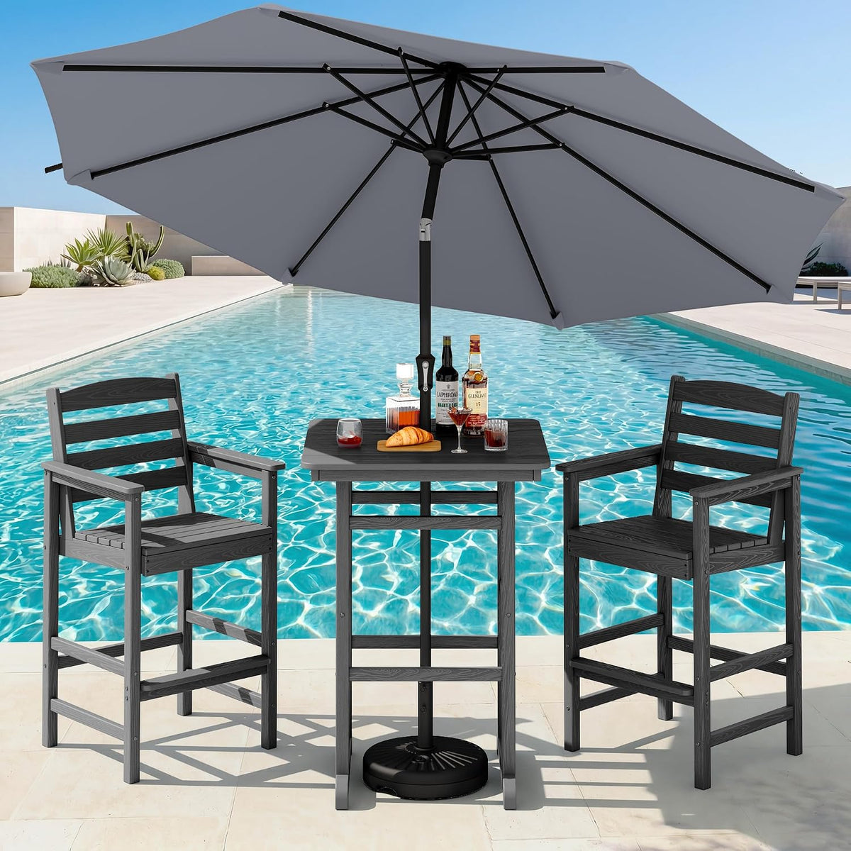 Three-piece dark gray bar-height table and two matching chairs by a pool under a gray umbrella