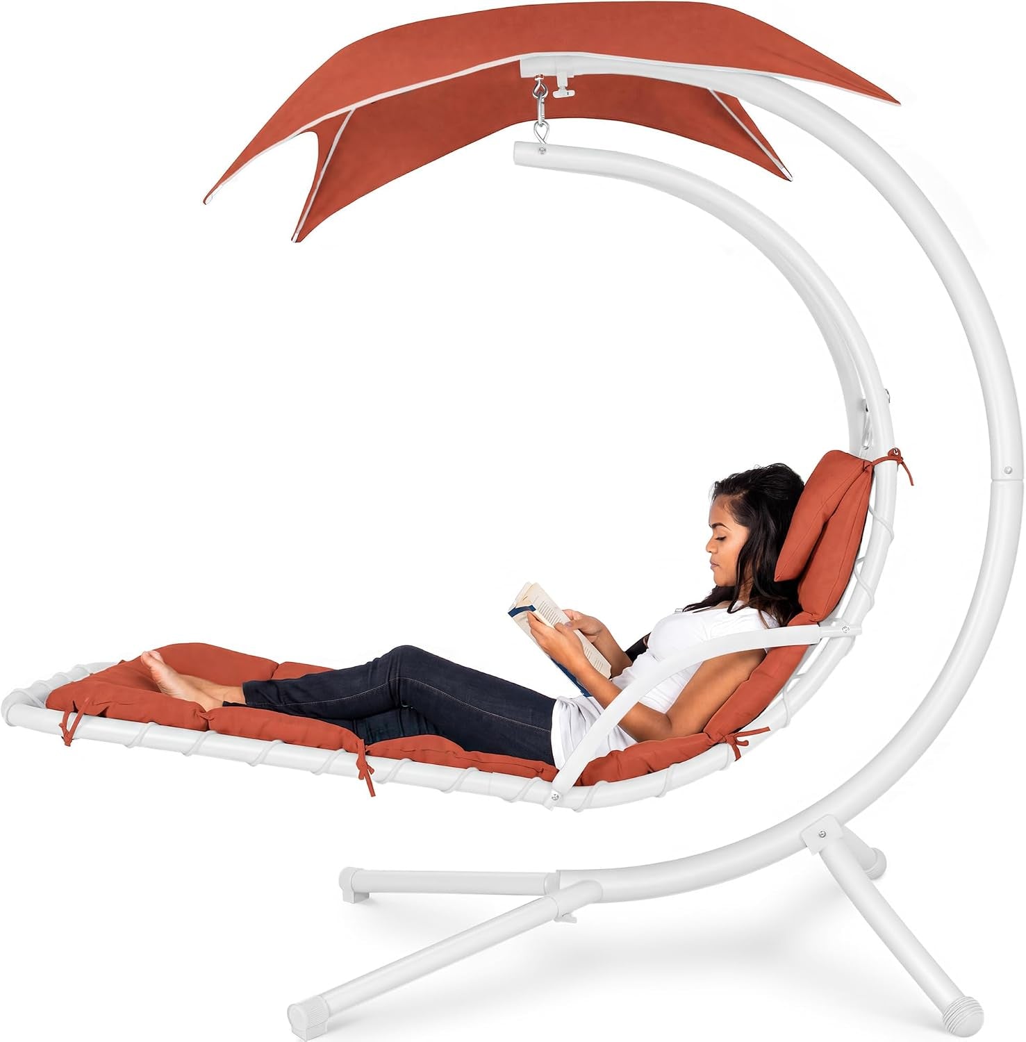 Curved hanging chaise swing in white frame with rust-colored cushions and canopy, woman reclining