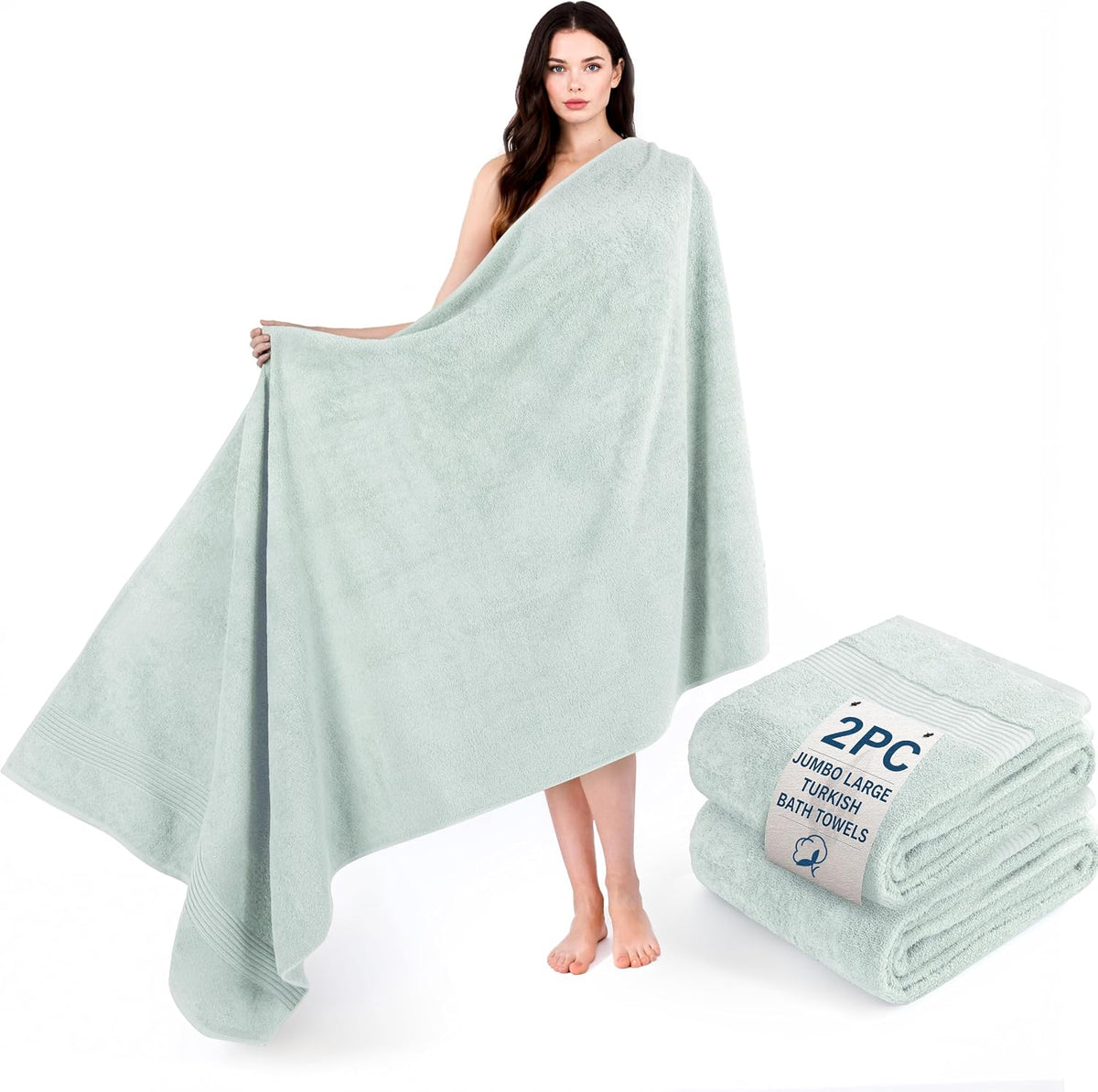 Woman draped in a large pale mint towel, with a matching folded towel stack nearby