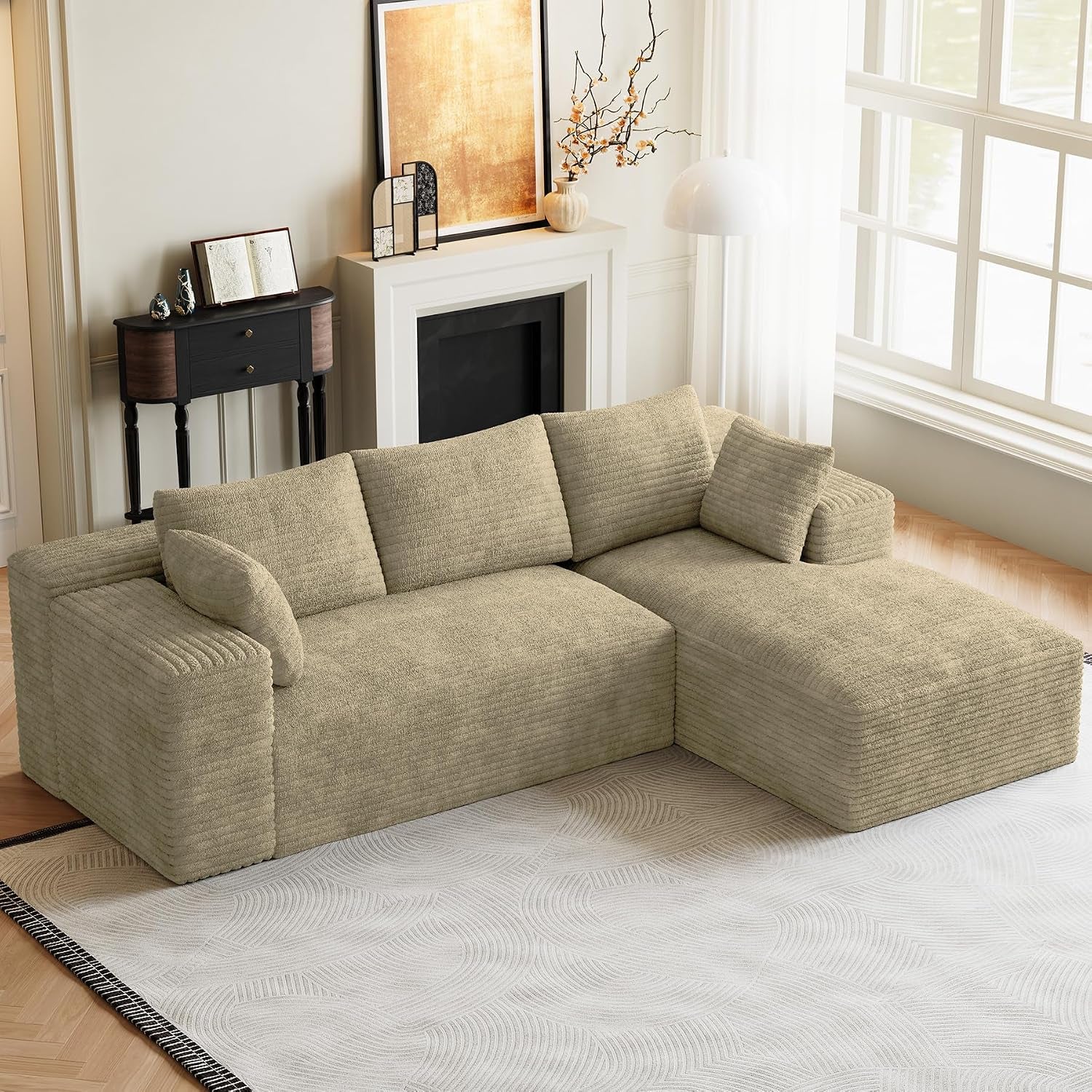 Beige modular sectional shown from an elevated angle with chaise on the right near a fireplace.