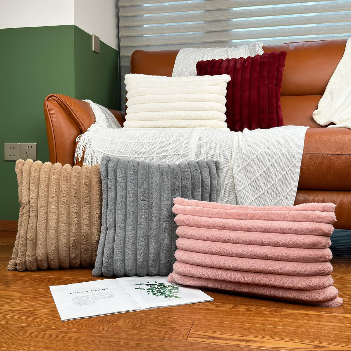 Cluster of five ribbed faux-fur lumbar pillows in beige, gray, pink and ivory arranged on floor and sofa