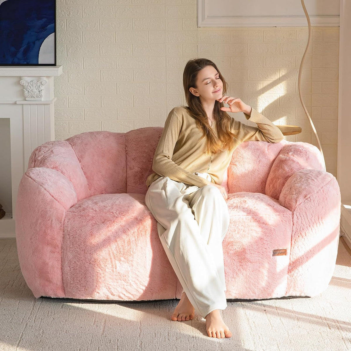 Woman reclining on a soft pink floral-shaped bean bag sofa with sunlight streaming across it.