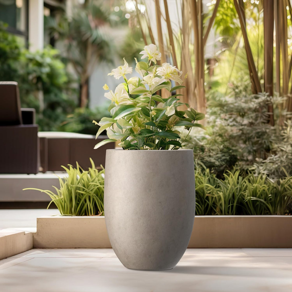 Close view of a round concrete planter on a patio surrounded by garden landscaping