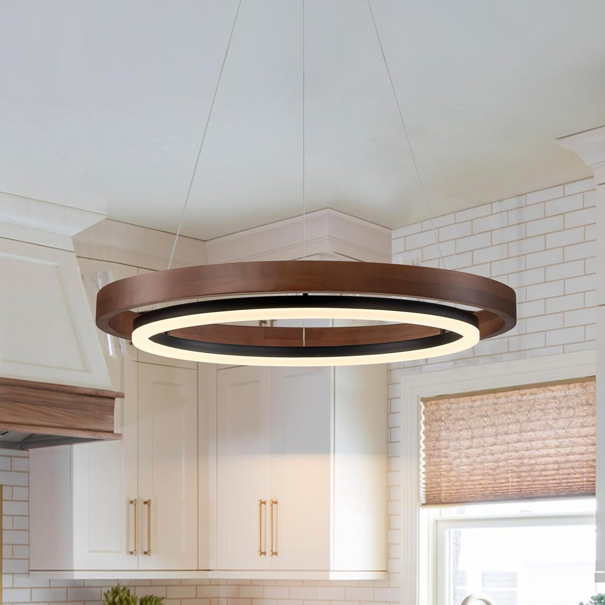 Round two-ring walnut wood chandelier hanging over a bright kitchen with white cabinets and tiled backsplash.