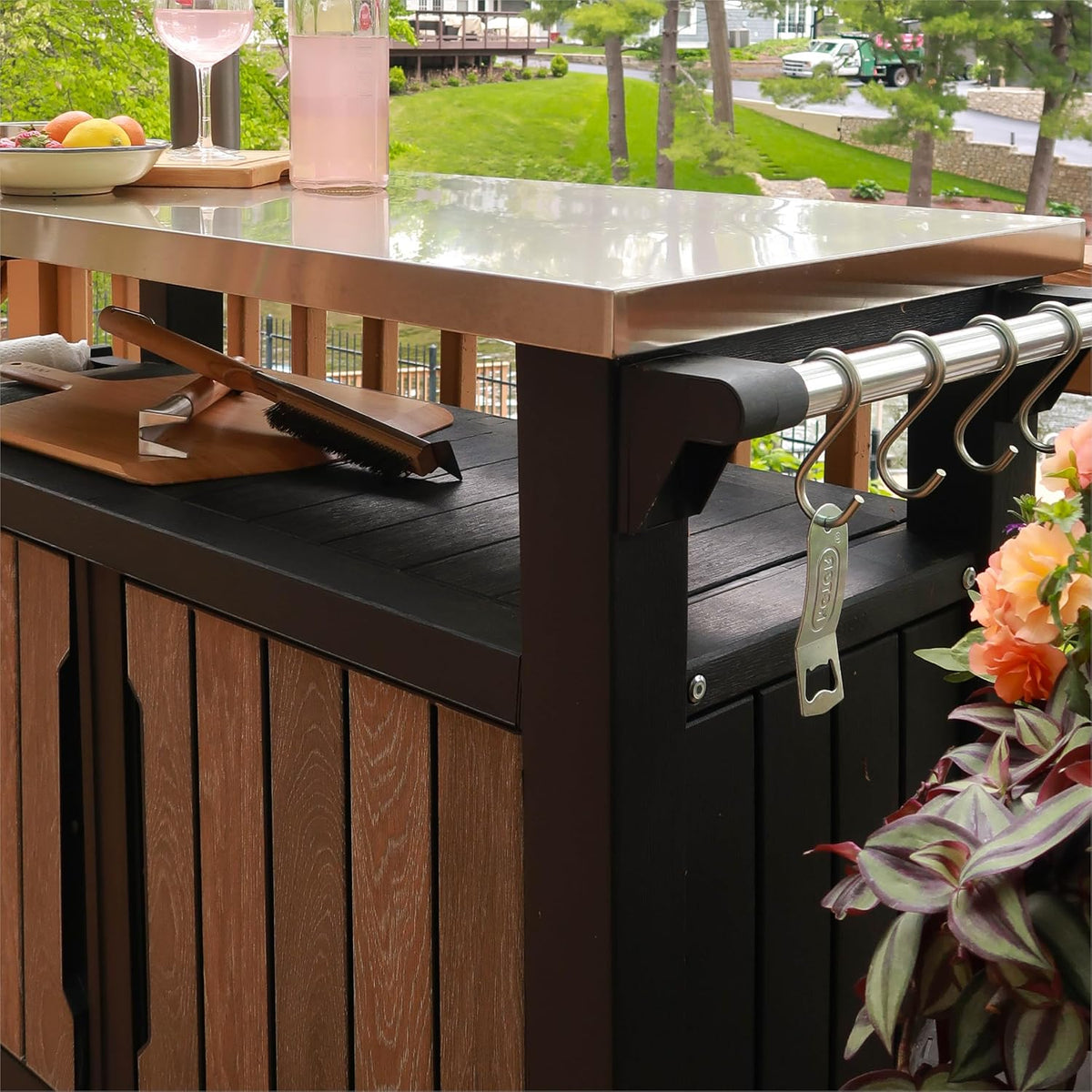 Angle showing the stainless-steel countertop, cutting board and a rail with S-hooks and a hanging bottle opener