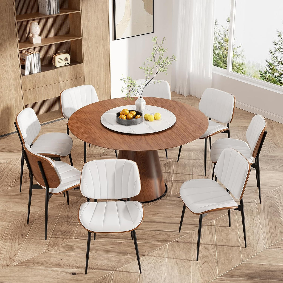 Overhead view of a round walnut table surrounded by eight white faux-leather chairs in a sunlit room.