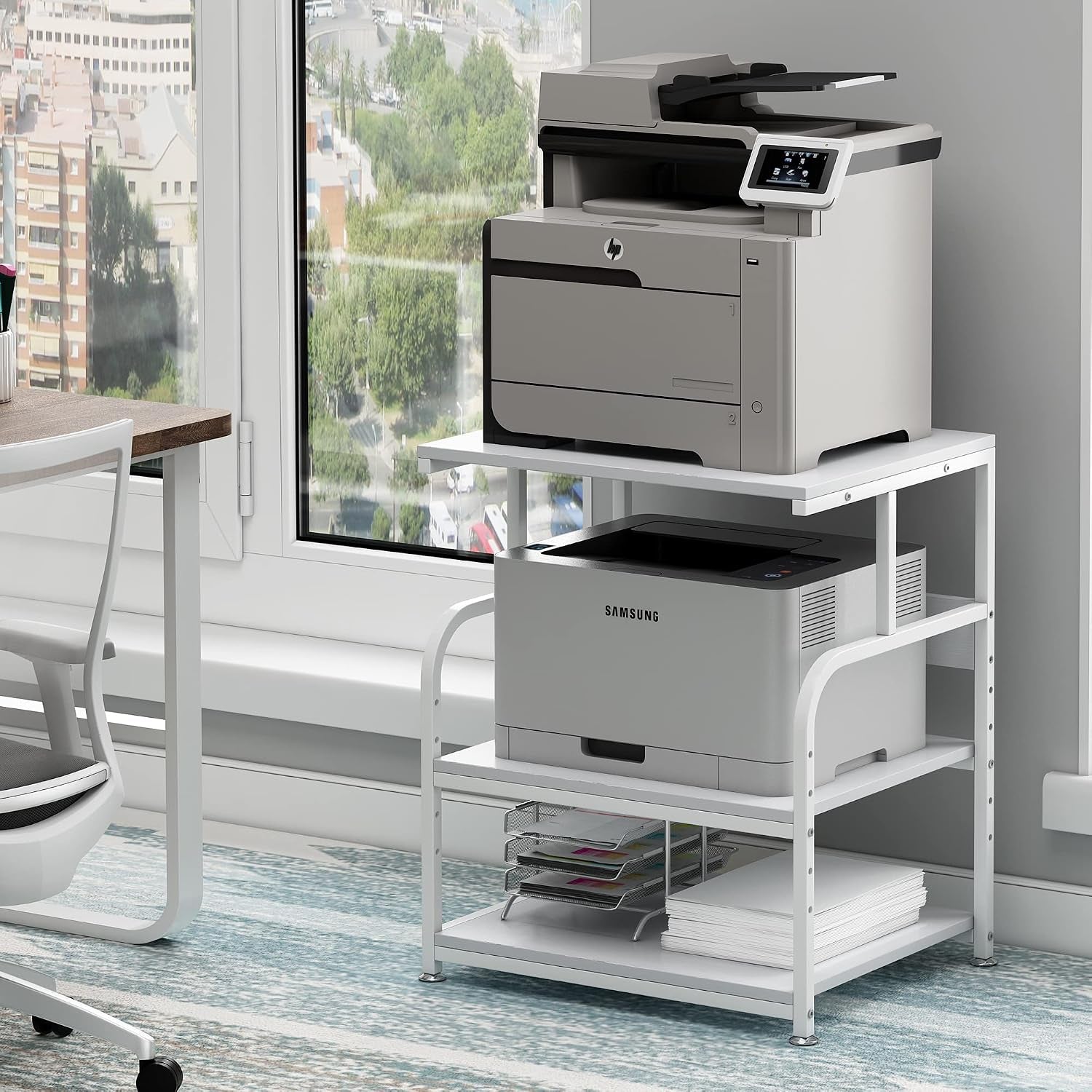 White printer stand beside a desk with white frame, two printers, and stacked paper on the lowest shelf.