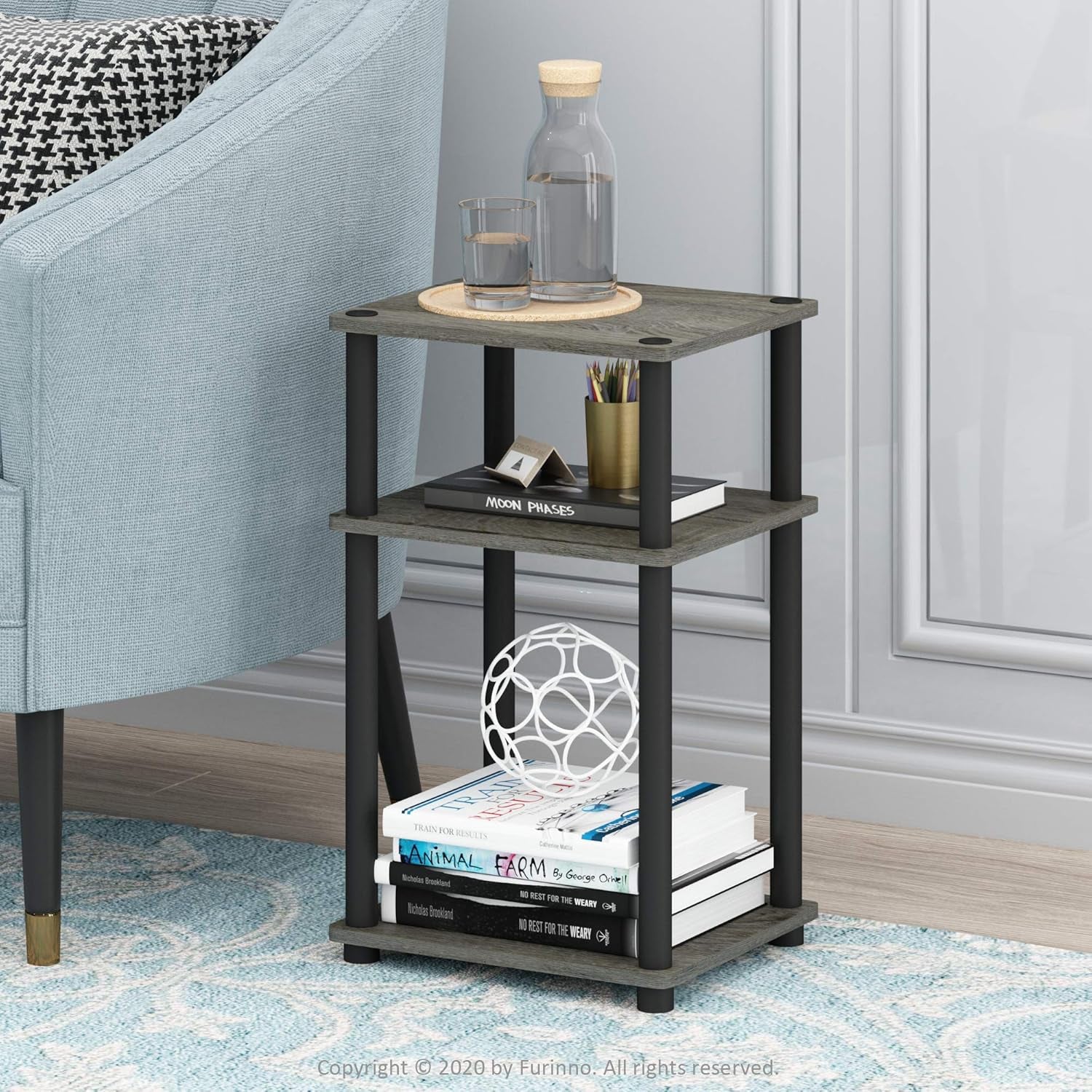 Small three-tier side table next to a light blue upholstered chair on a patterned rug