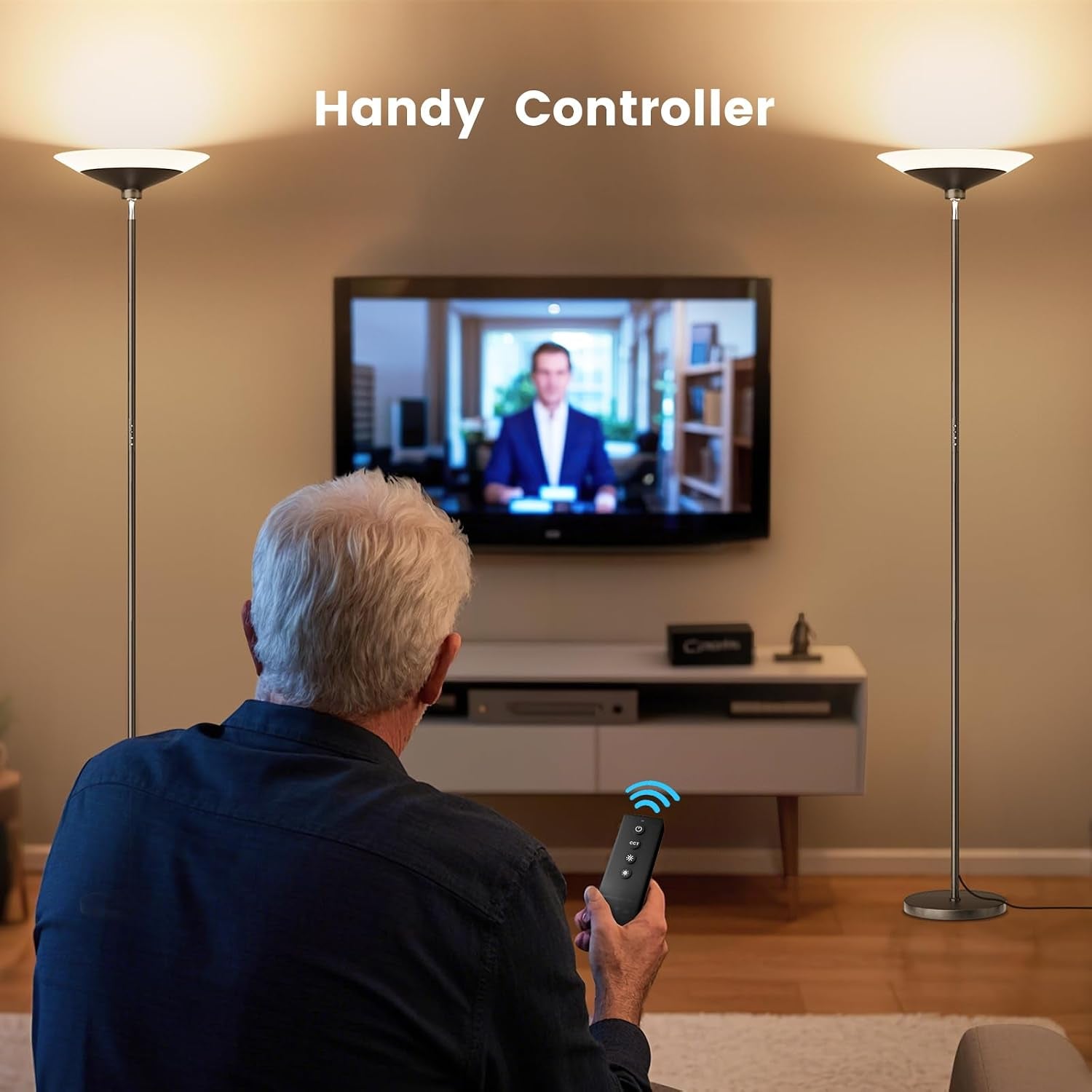 Man seated using the magnetic remote to control a torchiere lamp with two lamps visible in the living room background