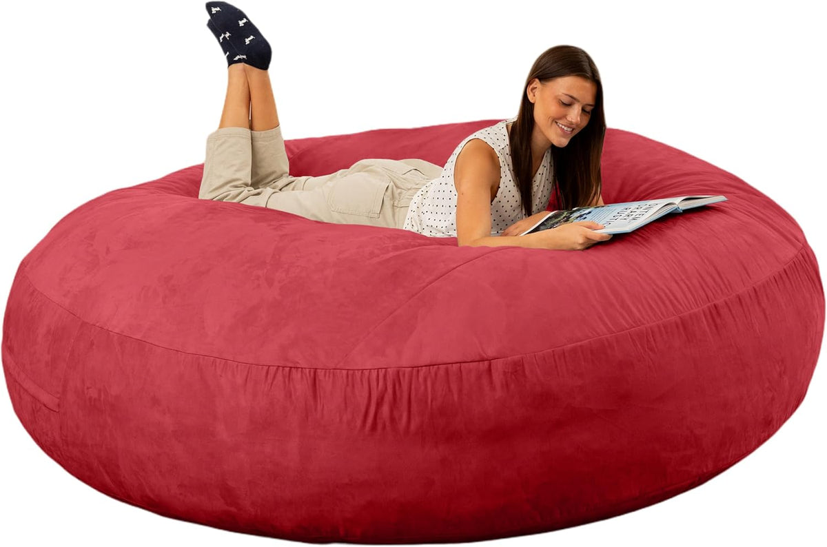 Angled top view of a large red round bean bag with a woman lying on it reading a magazine.