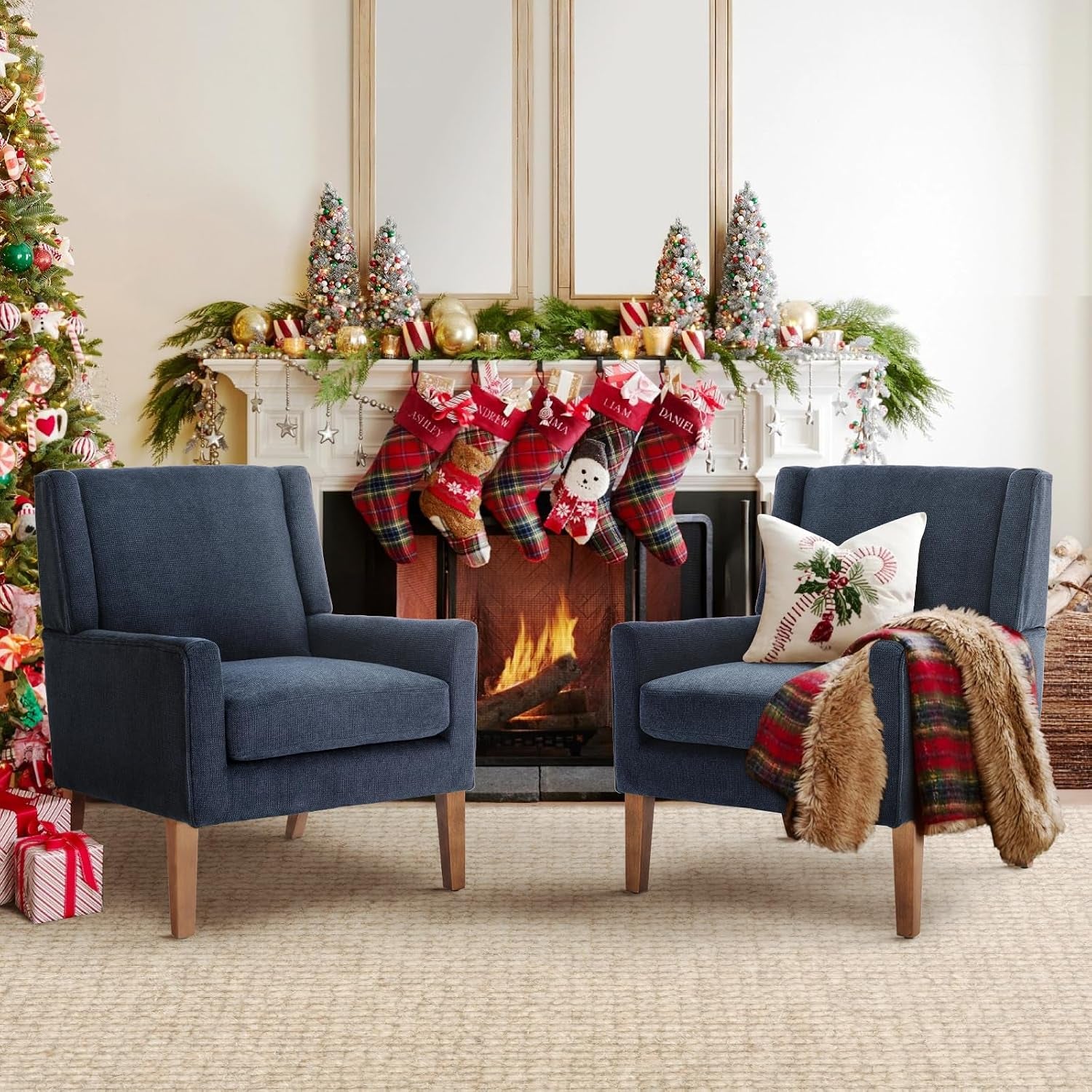 Pair of navy chenille wingback chairs with wood legs arranged by a fireplace with holiday stockings.