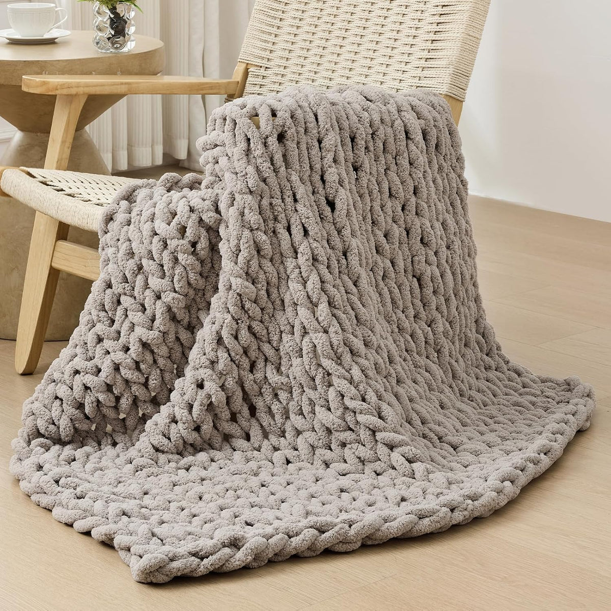 Light taupe chunky knit throw casually folded over a woven lounge chair.