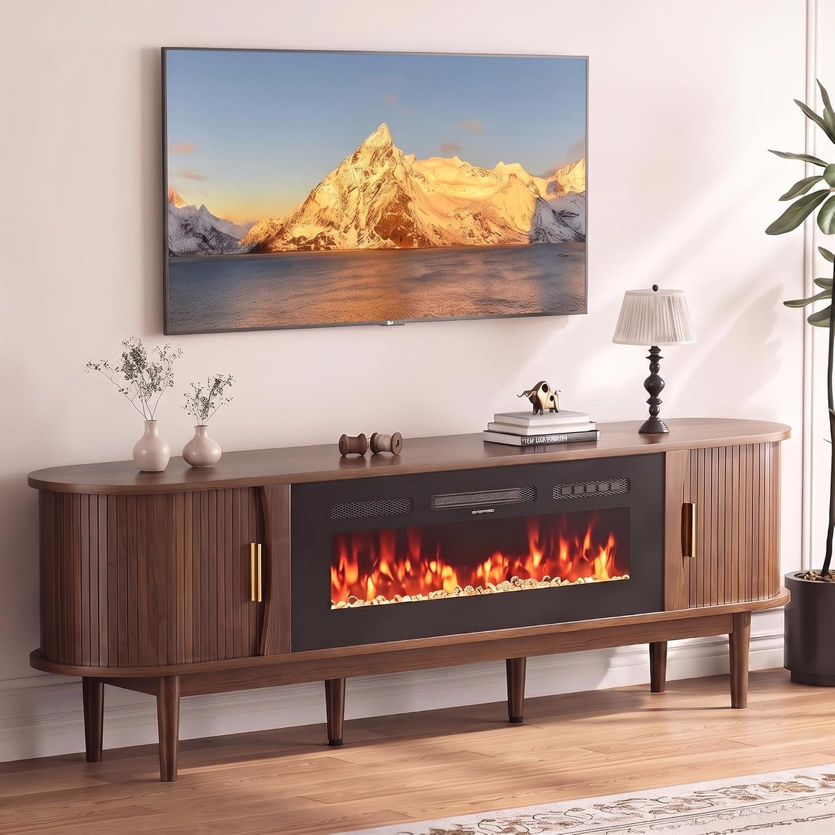 Close-up top view of walnut console showing rounded edges, tambour doors, and lit fireplace under a wall-mounted TV