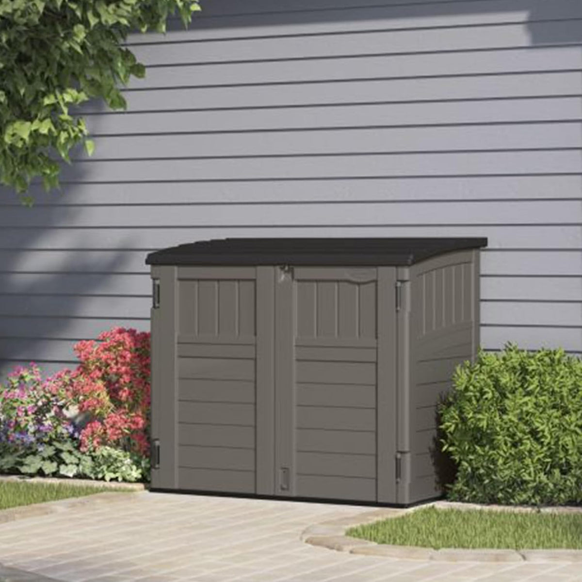 Compact Stoney Black horizontal storage shed set against house siding with nearby bushes and paving