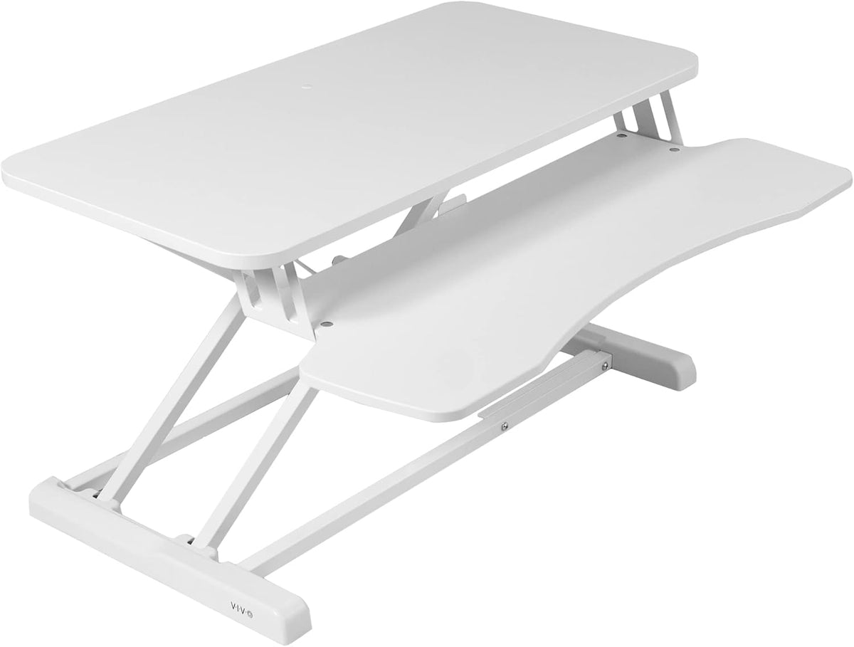 Angled three-quarter view of a white two-level standing desk converter showing keyboard tray and frame.