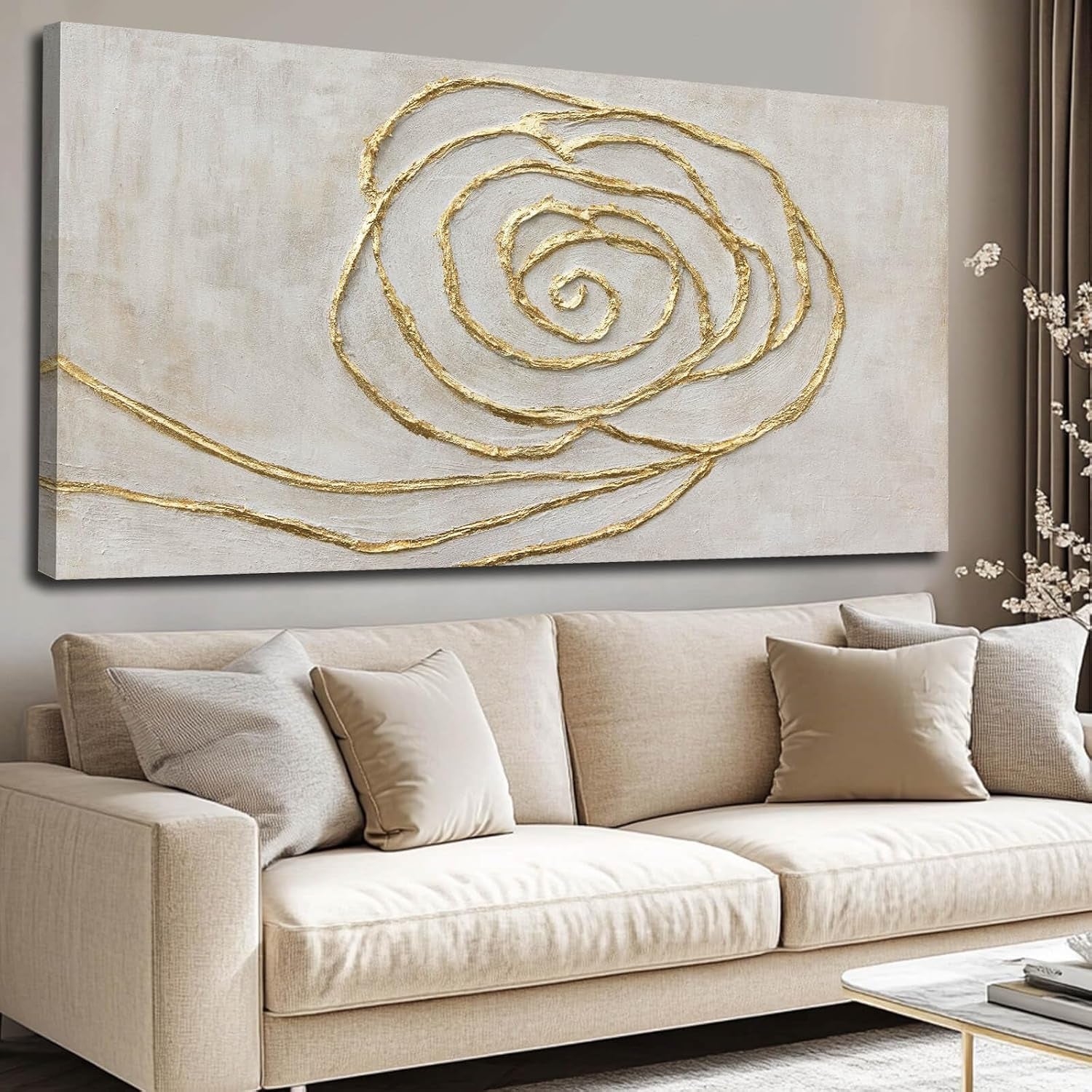 Front view of a neutral-toned canvas with raised gold spiral lines hung above a light beige sofa with matching pillows.